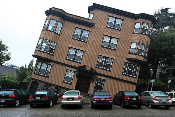Photo of an apartment building on a steep hill, with the camera tilted so that the building seems tilted and the street seems flat