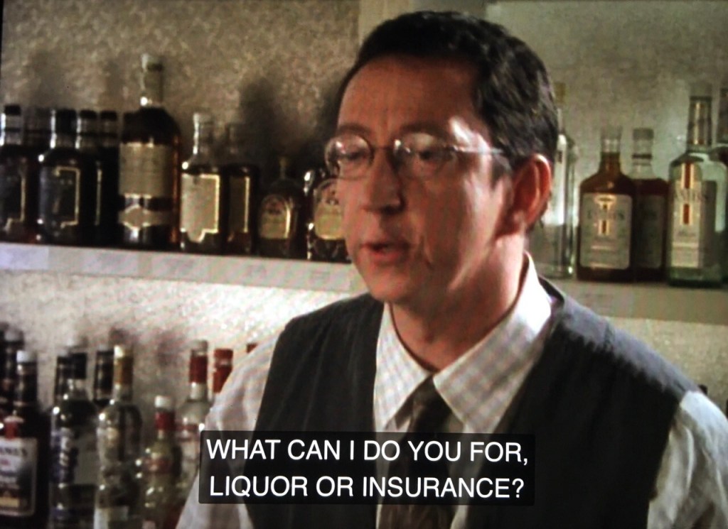 Bored looking bartender asks, "what can i do for you, liquor or insurance?"